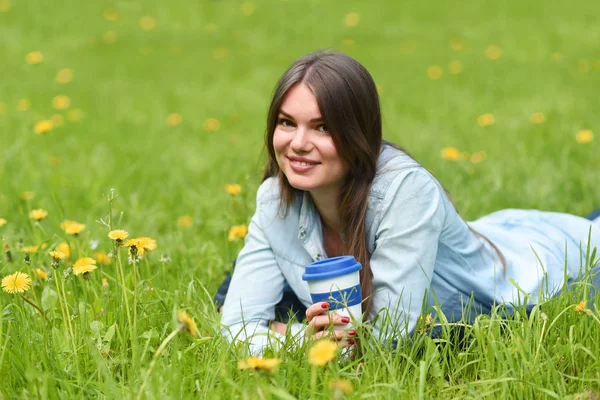 Mujer acostada en la hierba con café — Foto de Stock
