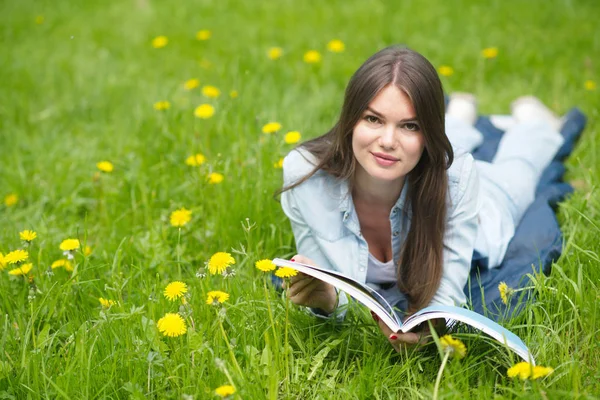 Woman lying on grass with magazine Stock Photo
