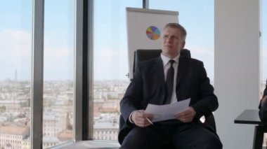Bir grup iş adamı ofis masasında veri mali raporlarını analiz etmeyi tartışıyor.