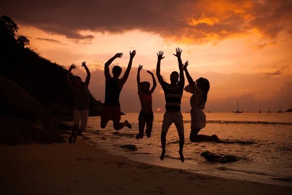 Friends on beach at sunset — Stock Photo, Image