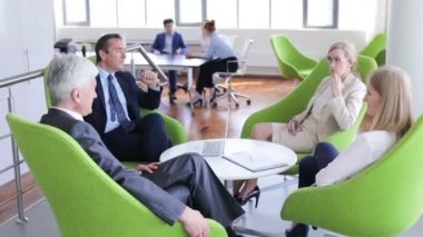 İş adamları ofis salonunda koltuklarda birlikte oturup tartışıyorlar