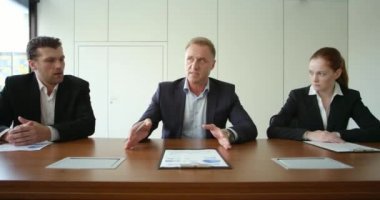 Toplantı masasında iş adamları, finansal istatistikleri gösteren raporlar ve ishal ile belgeleri tartışır