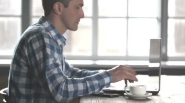 Bilgisayar dizüstü bilgisayar üzerinde çalışan ve coffe içme rahat giysiler içinde İş adamı