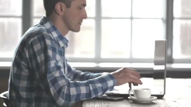 コンピューターのラップトップで働くカジュアルな服を着たビジネスマンと飲むコフ — ストック動画