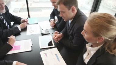 Ofiste masanın etrafında oturan finansal verileri tartışan iş adamları