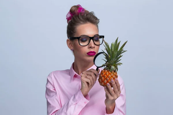 Kobieta patrzeć na ananasem przez lupę — Zdjęcie stockowe