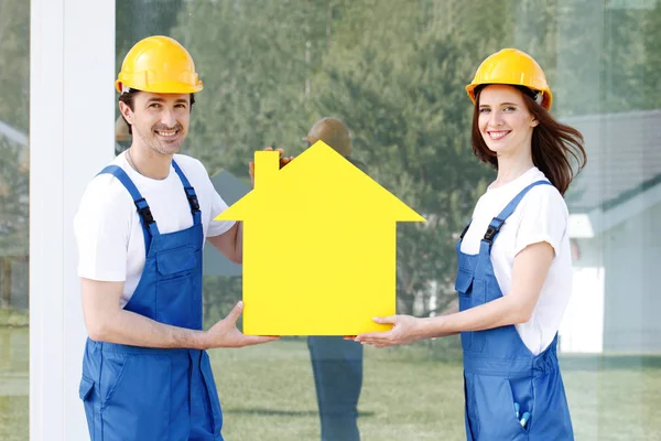 Dois trabalhadores mantêm modelo de casa — Fotografia de Stock
