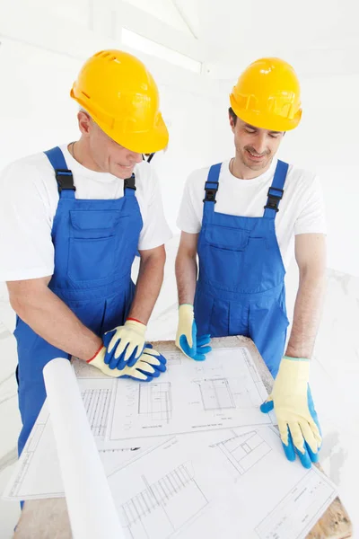 Byggare i hardhats med blueprint — Stockfoto