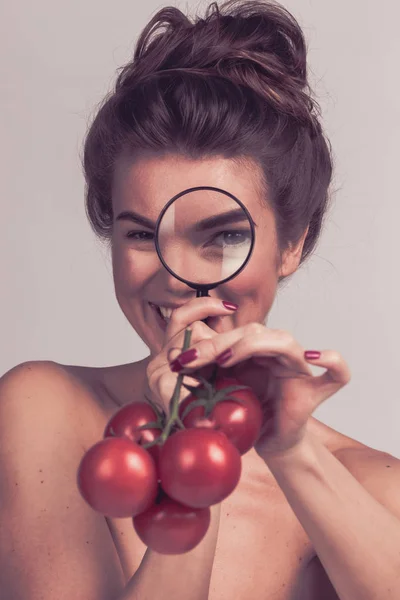 Dziewczyna badająca pomidory ze szkłem powiększającym — Zdjęcie stockowe
