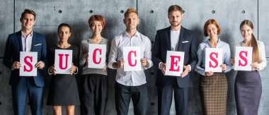 Kağıda basılmış SUCCESS mektupları tutan işadamları