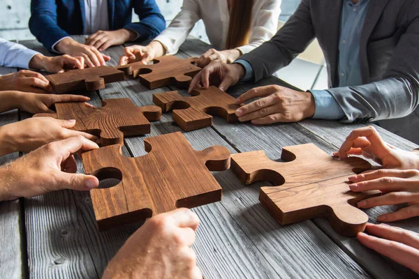 Business People Team Sitting Meeting Table Assembling Wooden Jigsaw Puzzle — Stock fotografie
