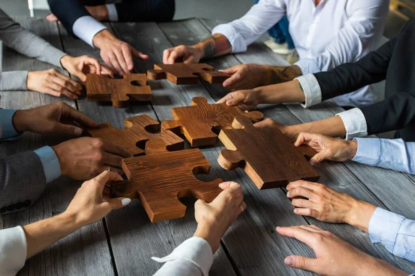 Business People Team Sitting Meeting Table Assembling Wooden Jigsaw Puzzle — Stock Photo, Image