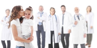 Anne kızını öpüyor, sağlık kliniğindeki doktor ekibi beyazlar içinde izole edilmiş.
