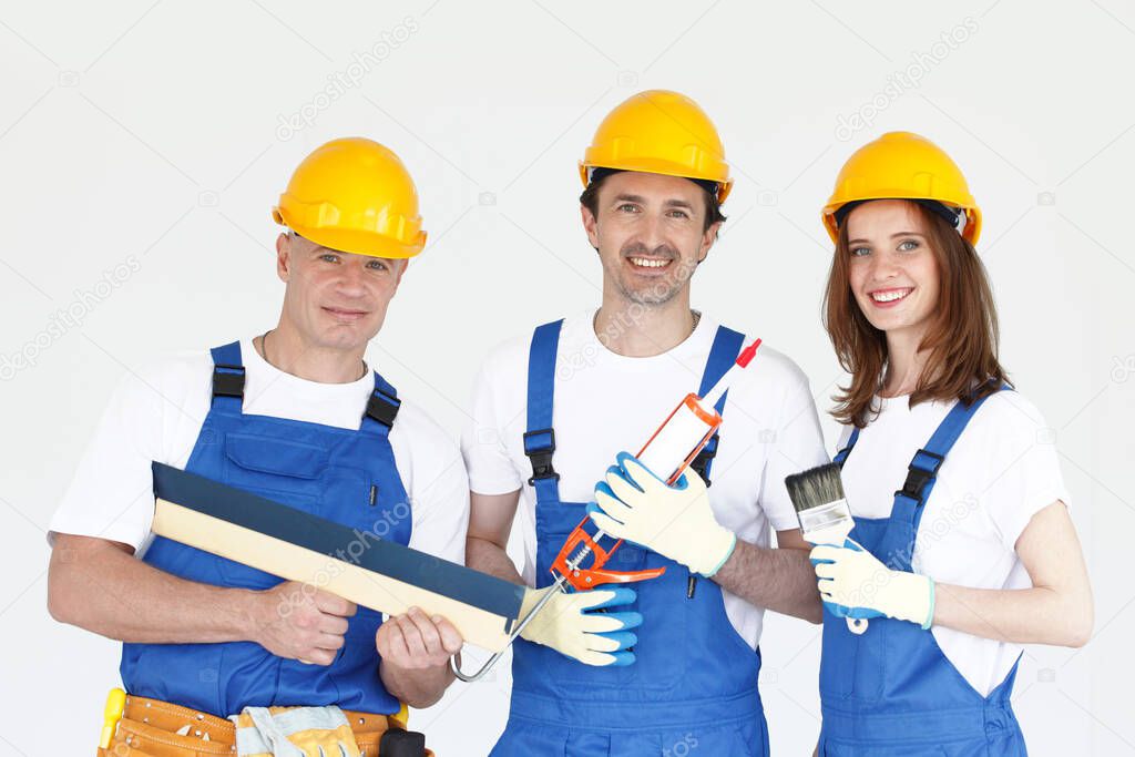Portrait of renovation workers in blue and yellow uniform with their tools on white
