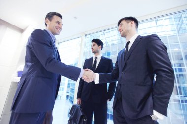 İş adamları el sıkışıyor, ofiste toplantıyı bitiriyor.