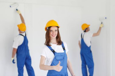 Kadın işçi, iki ressamın önünde baş parmağını kaldırıyor.