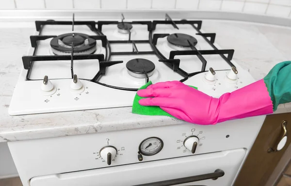 A mão em luvas de borracha limpa um fogão a gás de cozinha . — Fotografia de Stock