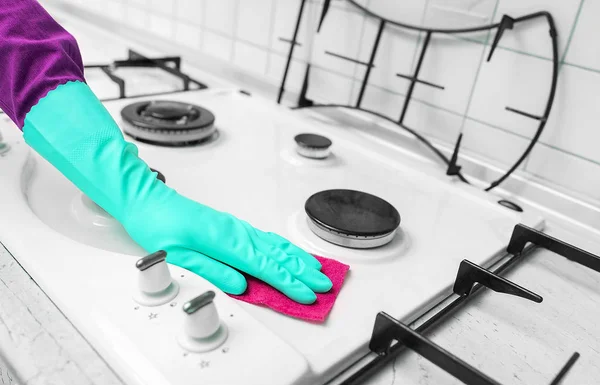 Main dans des gants en caoutchouc nettoie une cuisinière à gaz de cuisine . — Photo