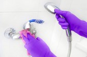 Gumi kesztyűt kezét mossa a zuhany alatt.