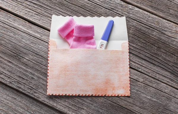 Prueba de embarazo en el sobre y calcetines para bebés . —  Fotos de Stock