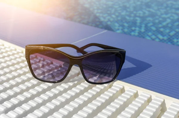 Occhiali da sole sul bordo della piscina. — Foto Stock