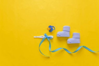 Bebek çorap ve sarı bir arka plan üzerinde bir hamilelik testi. Metniniz için bir yer var..