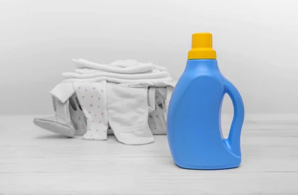 Botol dengan deterjen cair dengan latar belakang keranjang dengan pakaian bayi . — Stok Foto