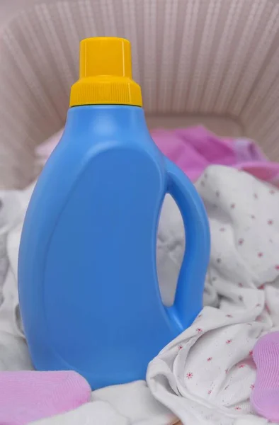 Bottle of laundry detergent in the basket with dirty baby clothes. — Stock Photo, Image