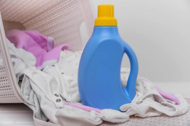 Deterjan kirli bebek giysileri ile sepete şişe.