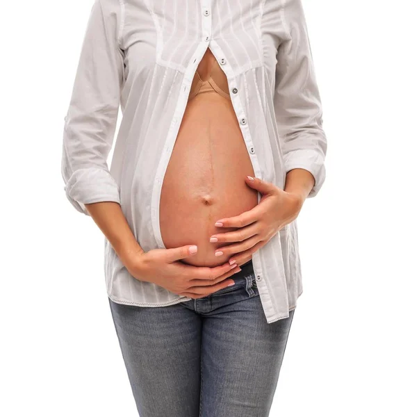 Mujer embarazada con camisa blanca y jeans sobre fondo blanco . — Foto de Stock