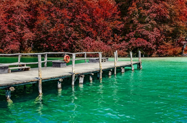 Um cais de madeira em um lago de montanha com água limpa . — Fotografia de Stock
