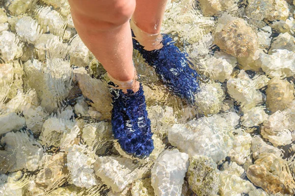 Feet in the water wrapped in special shoes to protect from sea urchins.