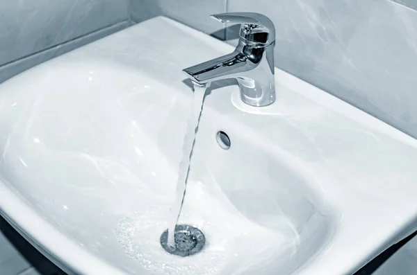 Mosogató és csaptelep áramlik a víz a fürdőszobában. — Stock Fotó