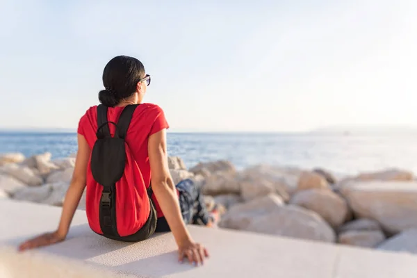 Woman traveler. Young woman sits on the beach in the rays of sunset. — Stock Photo, Image