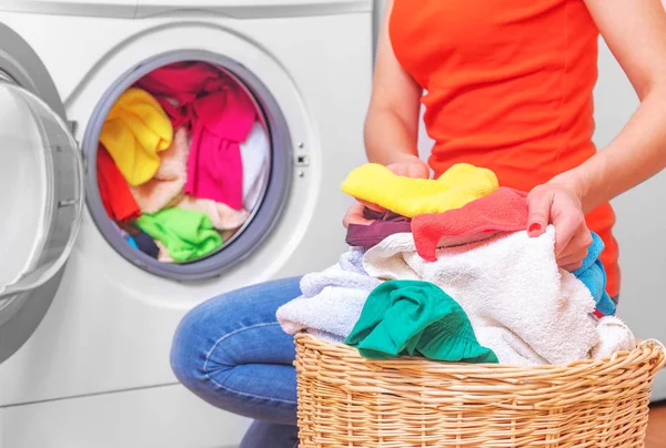 Jeune femme charge la lessive dans la machine à laver du panier à linge avant de laver . — Photo