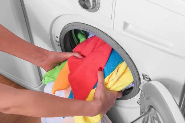 Jeune femme charge la lessive dans la machine à laver du panier à linge avant de laver . — Photo