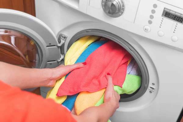 Junge Frau lädt die Wäsche vor dem Waschen aus dem Wäschekorb in die Waschmaschine. — Stockfoto