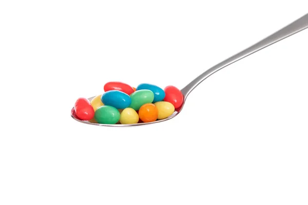 Multi-colored permen dalam sendok pada latar belakang putih . — Stok Foto