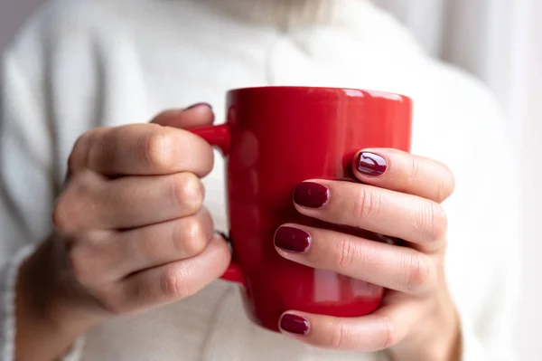 Junge Frau hält eine Tasse mit einem heißen Getränk in der Hand. — Stockfoto