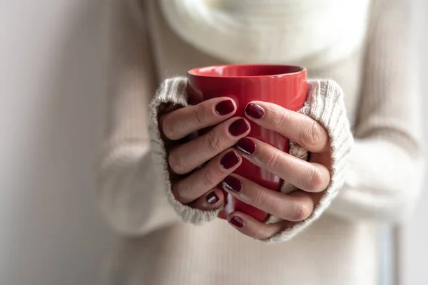 Junge Frau hält eine Tasse mit einem heißen Getränk in der Hand. — Stockfoto
