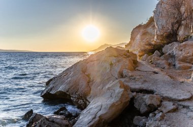 Kayalar ve çam deniz kıyısında günbatımı.