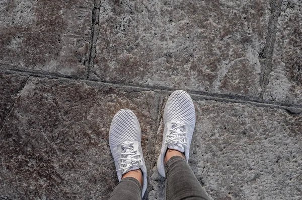 Patas de mujer en zapatillas blancas en el pavimento . — Foto de Stock