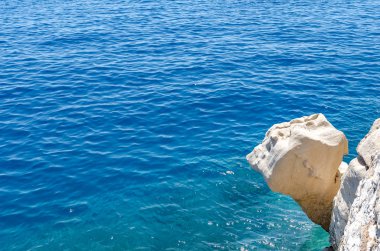 Mavi denizin üzerindeki taş uçurum veya kayalık çıkıntı.