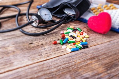 Ahşap arka plan üzerinde tonometre hapları ve kalp modeli.