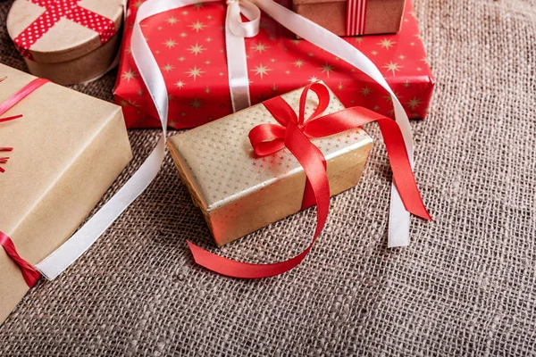 Cajas de Navidad con regalos sobre fondo de arpillera . — Foto de Stock