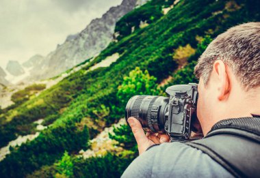 Ormanda kamera tutan fotoğrafçı adam.