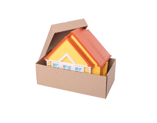 Modelo de brinquedo de uma casa em uma caixa de papelão no fundo branco . — Fotografia de Stock