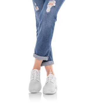 Beyaz arka planda izole kot pantolon ve beyaz spor ayakkabı bacaklar.