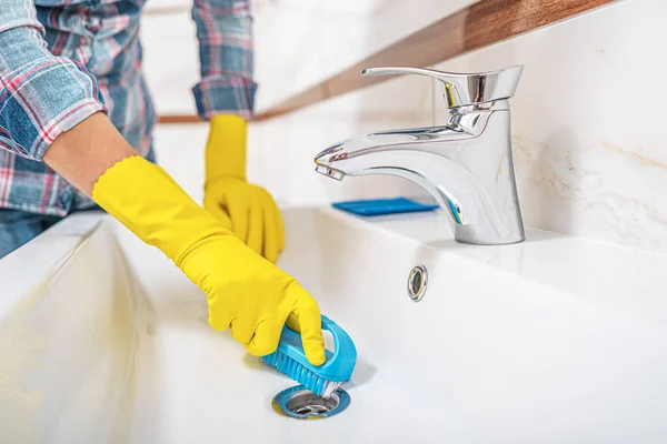 Nettoyage dans la salle de bain. Une femme essuie l'évier et le robinet de lavabo . — Photo