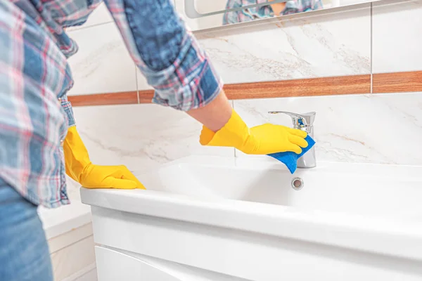 Sprzątanie w łazience. Kobieta wyciera zlew i umywalki kran. — Zdjęcie stockowe